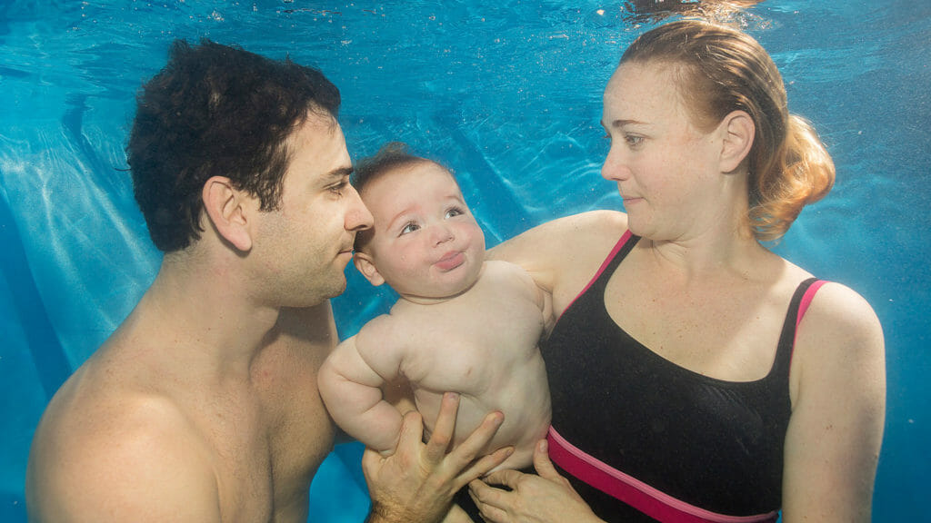 baby learning to swim with mum and dad