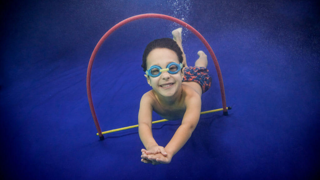 child swimming through a hoop underwater