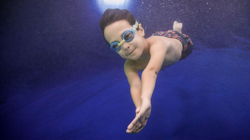 child swimming underwater in a holiday course